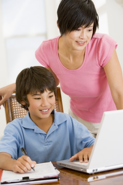 woman helping young boy with laptop