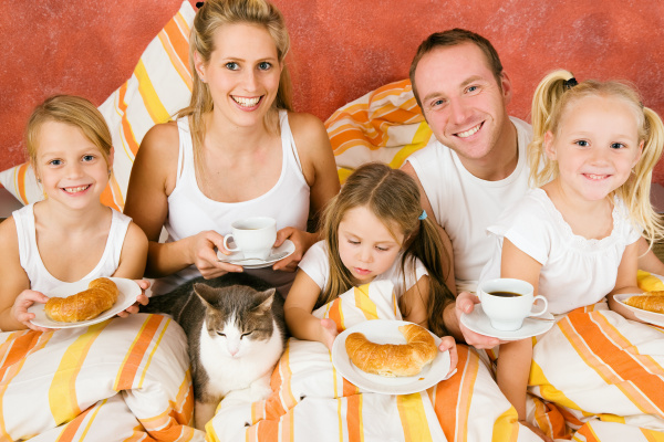 family with cat in bed at