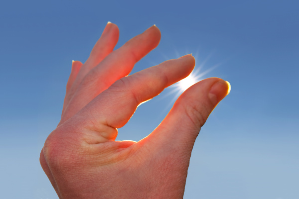 sun with rays between fingers of