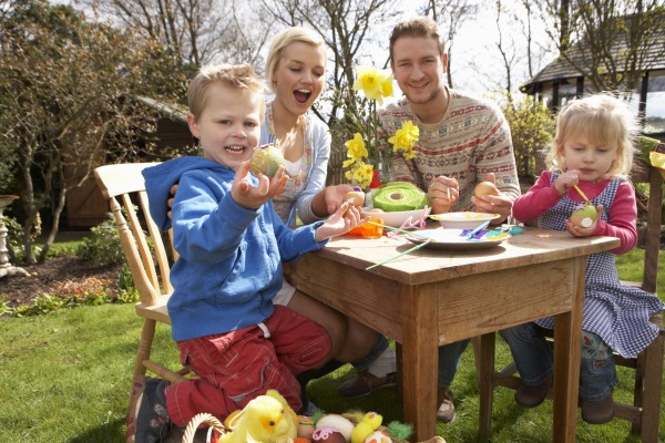 family decorating easter eggs on table