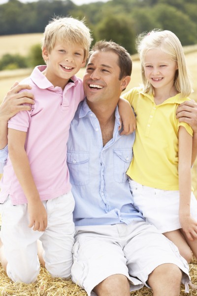 father and children sitting on straw