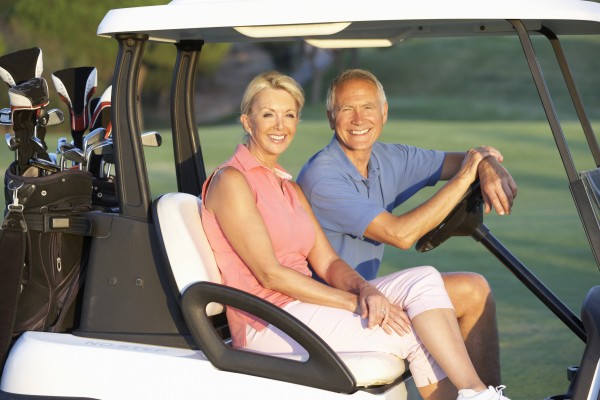senior couple riding in golf buggy