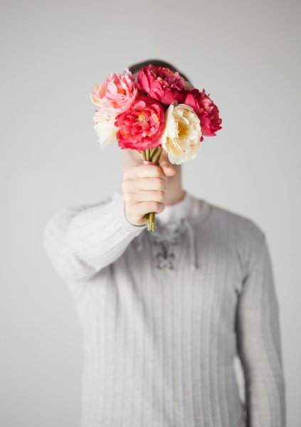 man covering his face with bouquet