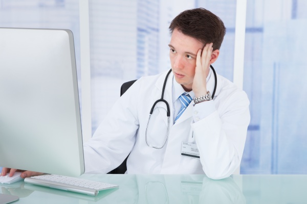worried male doctor using computer at