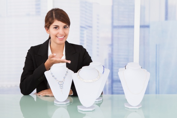 confident saleswoman displaying jewelry at desk