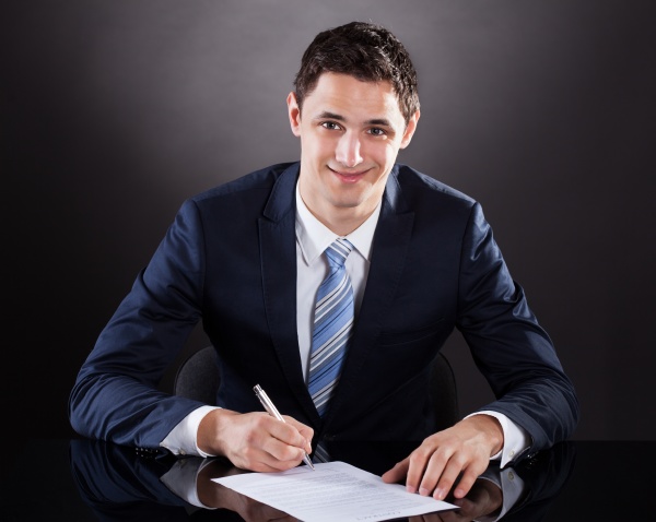 young businessman signing contract at desk