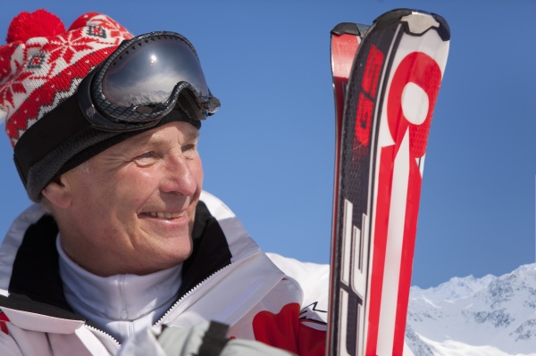 smiling man standing holding skis