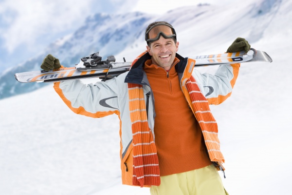smiling man holding skis on mountain
