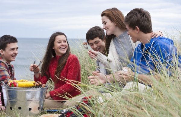 teenage friends enjoying barbecue in grass