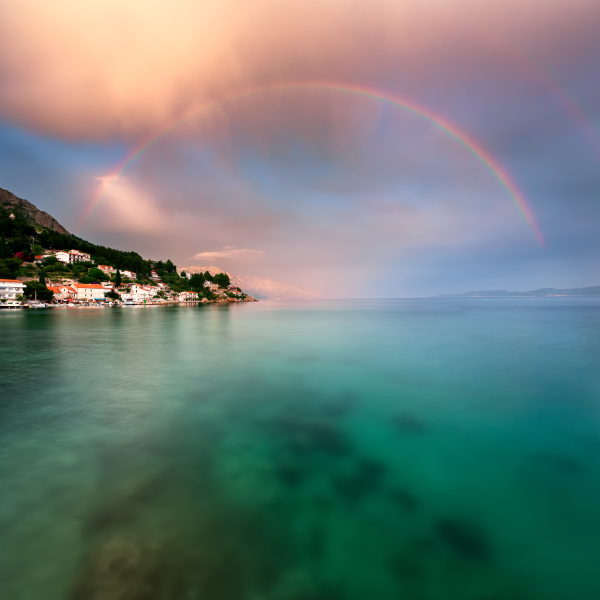 rainbow over rocky beach and small