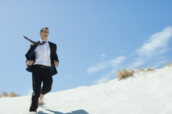 businessman running across sand dune