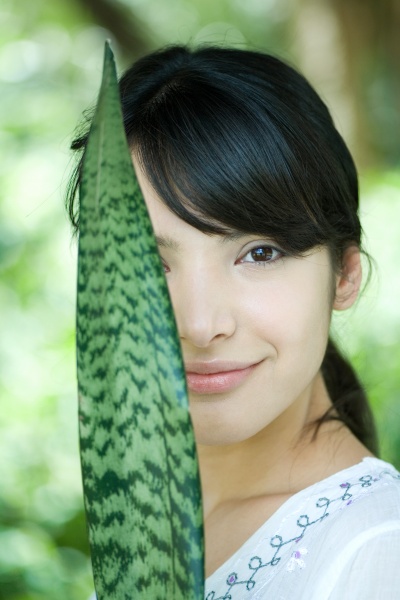 woman holding up snake plant leaf