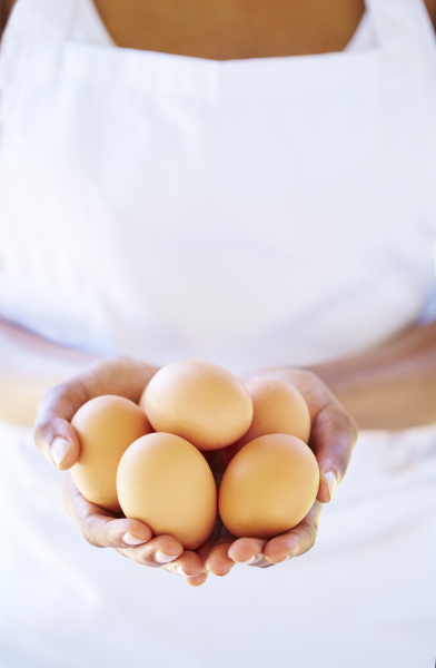 woman s hands holding brown eggs