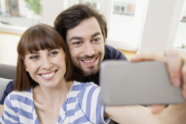 happy couple taking selfie at home
