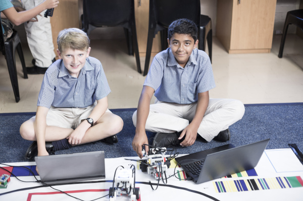 two smiling schoolboys with laptops in