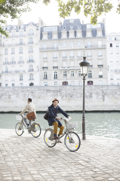 men riding bicycles along seine river