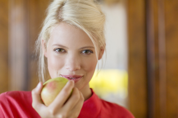 woman eating apple indoors