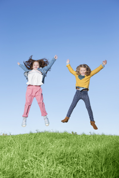girls jumping for joy on grassy