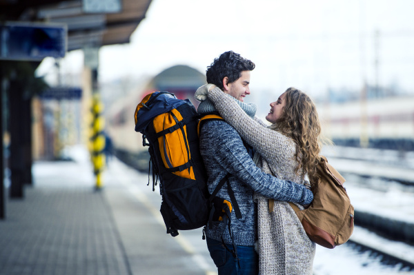smiling young couple embracing on station