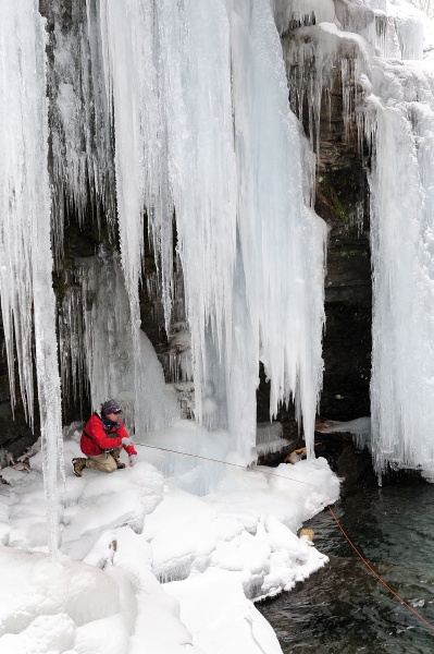 a man fly fishing under icicles