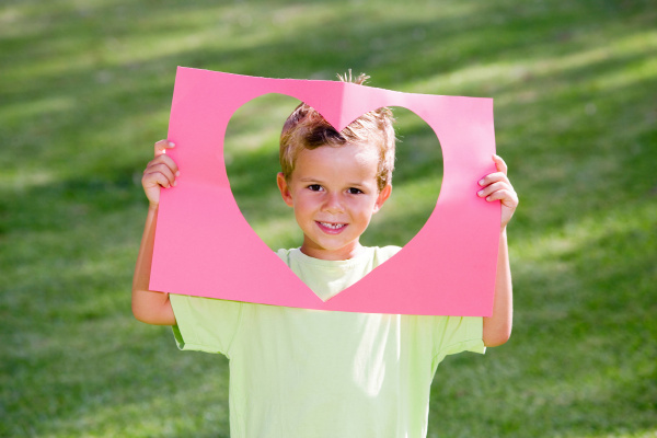 young boy holding paper heart frame