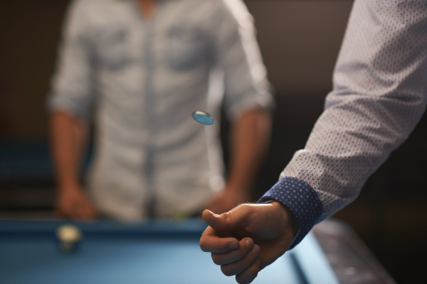 man tossing coin at pool table