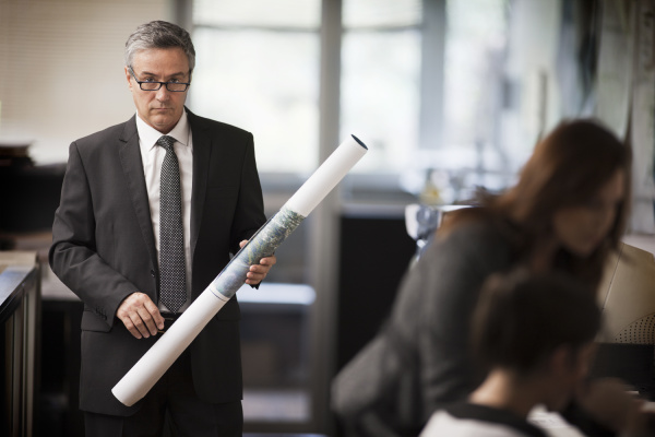 mature businessman holding a tall roll