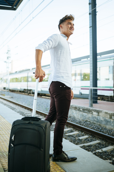young, man, with, suitcase, waiting, at - 19316917