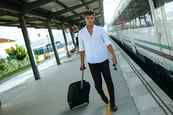 young man with suitcase walking at