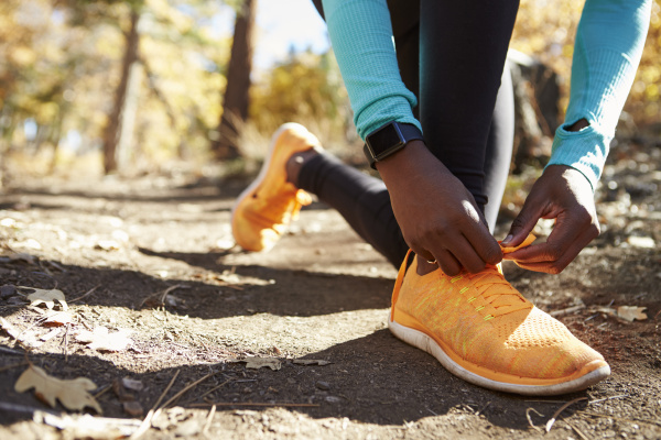 black female runner in forest tying