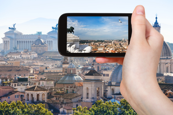 tourist photographs rome skyline on smartphone