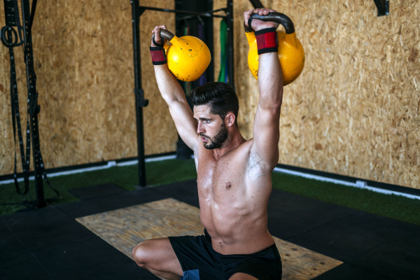 man lifting kettlebells in gym