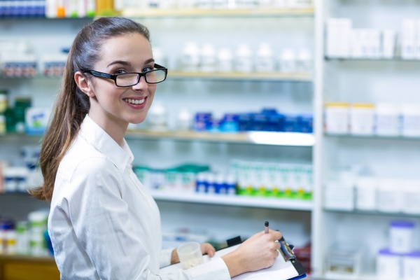 pharmacist writing on clipboard in pharmacy