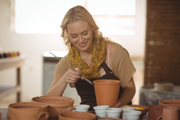 beautiful female potter painting on pot