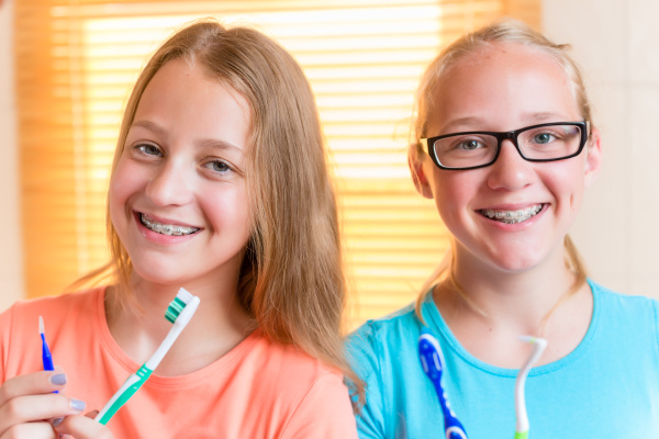 two girls with dental retainers brushing