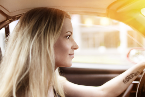smiling blond woman driving car