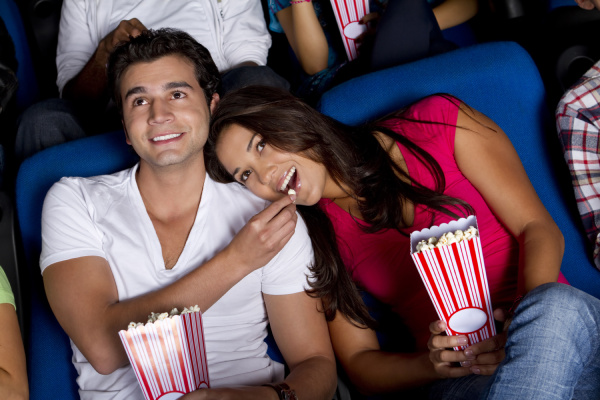 hispanic couple enjoying popcorn at movie
