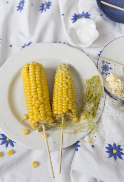 two corn cobs with butter and