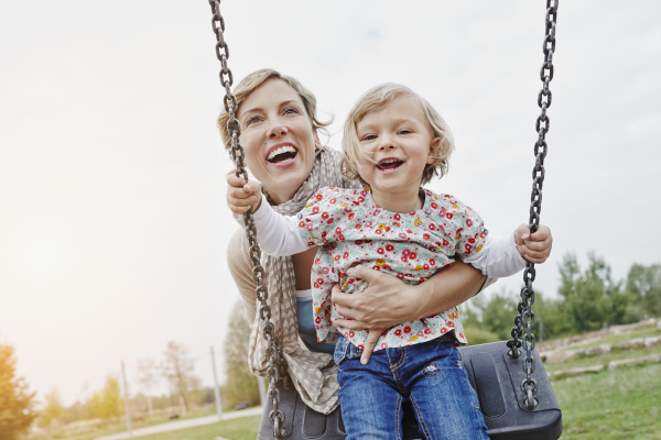 mother with daughter on swing on