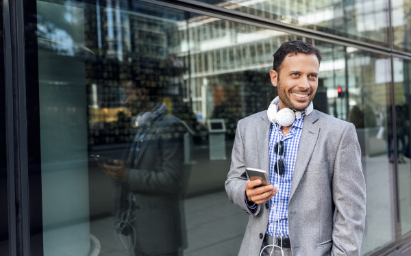 smiling businessman with headphones and cell