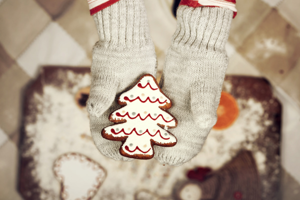 child hands in gloves holding gingerbread
