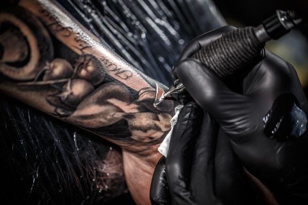 artist tattooing of man s skin