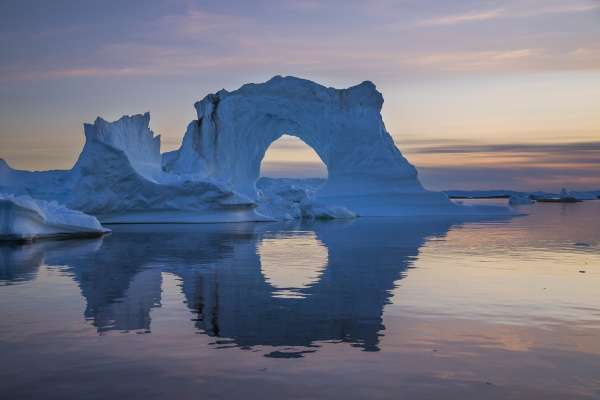 natural arch of towering iceberg reflecting