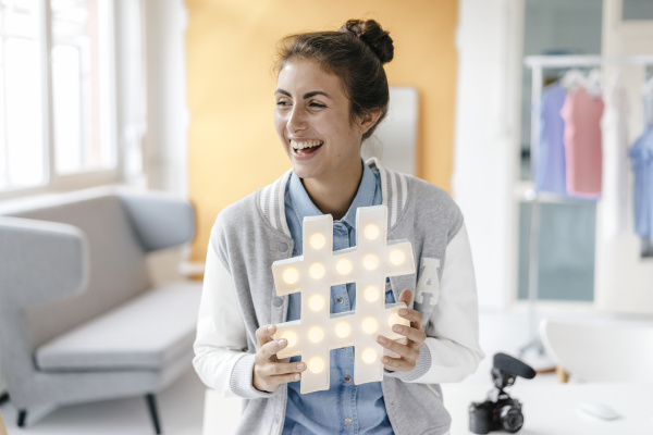 laughing young woman holding hashtag sign