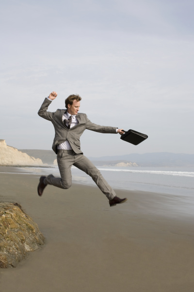 businessman jumping on beach