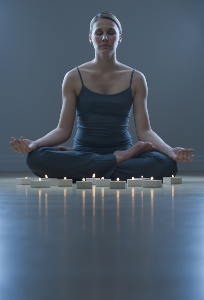 woman meditating next to candles