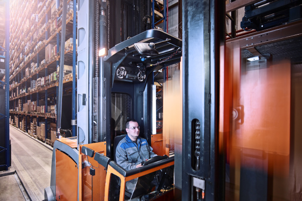 worker operating high rack in storehouse