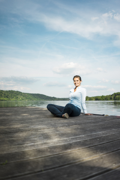smiling woman sitting on jetty at