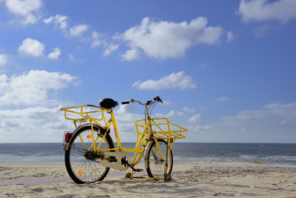 yellow bicycle stands on the beach