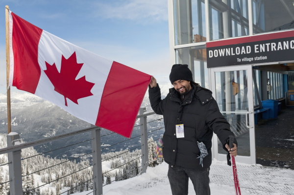 a skiier holds up a canadian